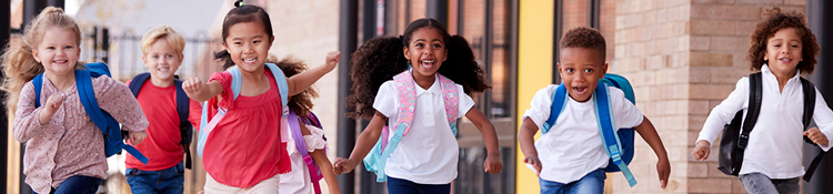 Image of children running and smiling outside of a school facility.